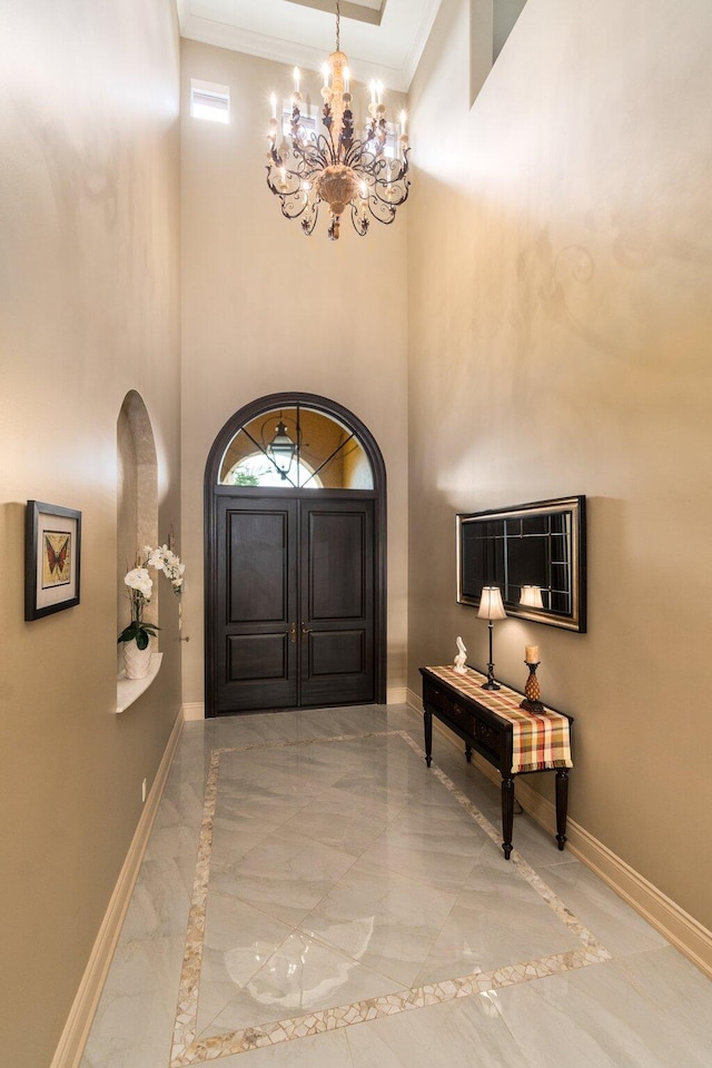 foyer with a high ceiling, an inviting chandelier, and ornamental molding