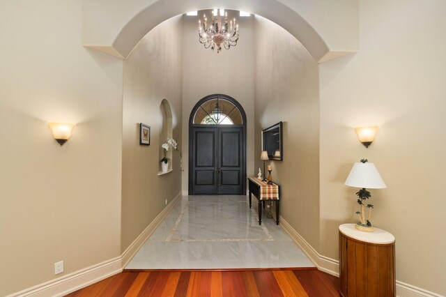 entrance foyer with wood-type flooring, a high ceiling, and a notable chandelier