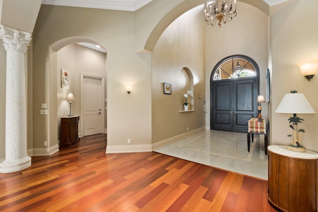 foyer with wood-type flooring, crown molding, a high ceiling, and an inviting chandelier