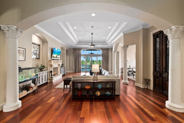 dining room with dark hardwood / wood-style flooring, a tray ceiling, and ornate columns