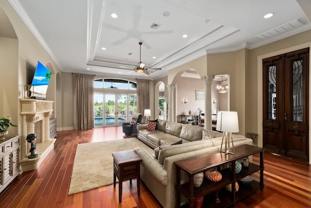 living room with a tray ceiling, ceiling fan, dark hardwood / wood-style flooring, and ornamental molding