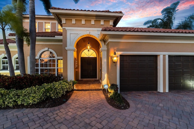 exterior entry at dusk featuring a garage