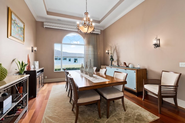 dining room with an inviting chandelier, crown molding, a tray ceiling, and light hardwood / wood-style flooring