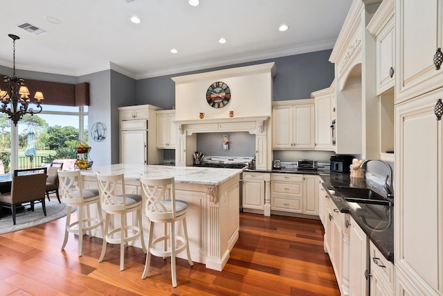 kitchen featuring dark hardwood / wood-style flooring, sink, pendant lighting, a notable chandelier, and a center island