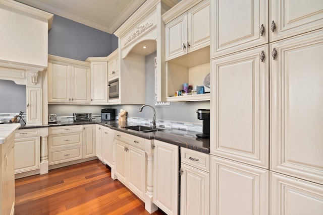 kitchen featuring dark hardwood / wood-style flooring, ornamental molding, sink, cream cabinetry, and stainless steel microwave