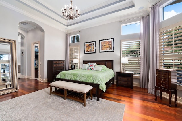 bedroom with a notable chandelier, ornamental molding, dark wood-type flooring, and a tray ceiling