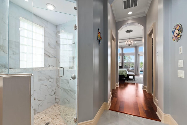 interior space featuring a chandelier, a shower with door, wood-type flooring, and ornamental molding