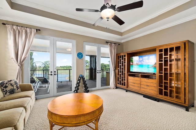 living room with a raised ceiling, french doors, and carpet