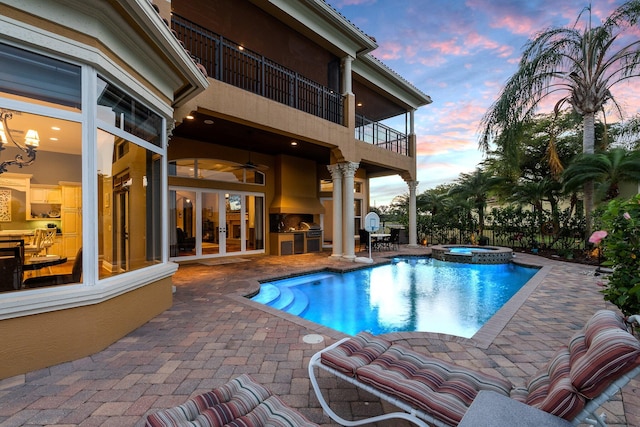 pool at dusk with area for grilling, a patio area, an in ground hot tub, and french doors