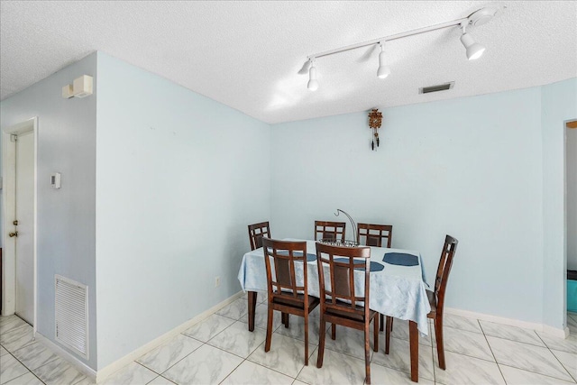 dining space with a textured ceiling and rail lighting