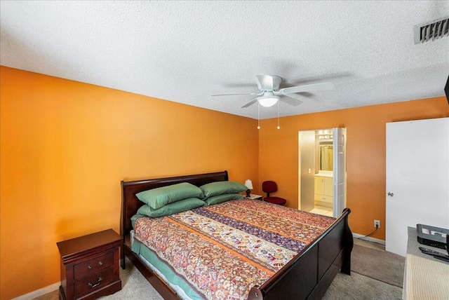 carpeted bedroom with a textured ceiling, ensuite bath, and ceiling fan