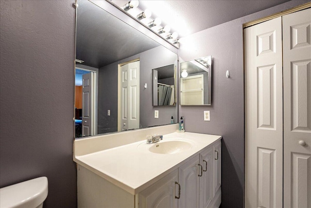 bathroom with a textured ceiling, vanity, and toilet