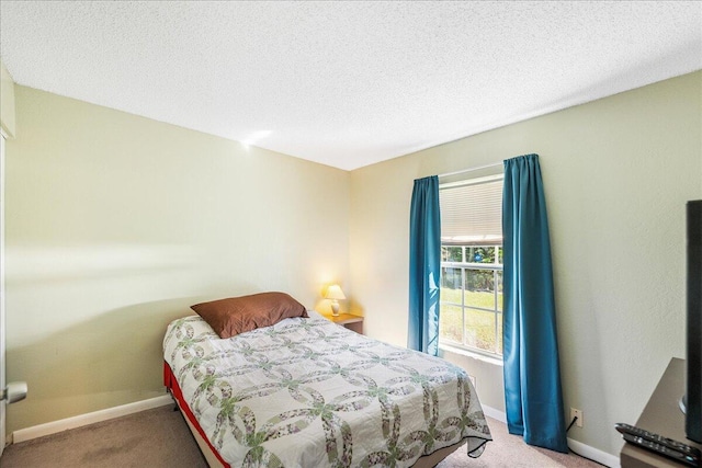 bedroom with light colored carpet and a textured ceiling