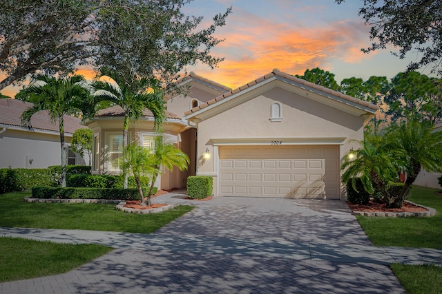 mediterranean / spanish-style house featuring a garage and a lawn