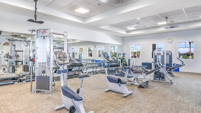 workout area with a towering ceiling, a paneled ceiling, light colored carpet, and a raised ceiling