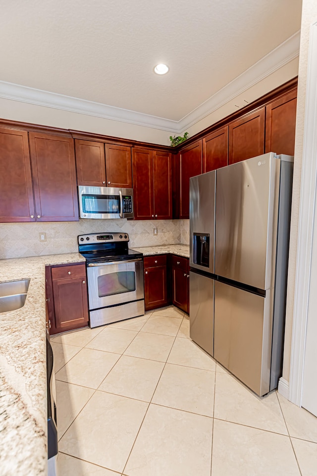 kitchen with light stone countertops, ornamental molding, stainless steel appliances, and light tile patterned flooring