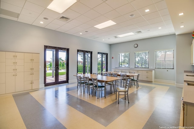 dining area with french doors, a towering ceiling, and a drop ceiling