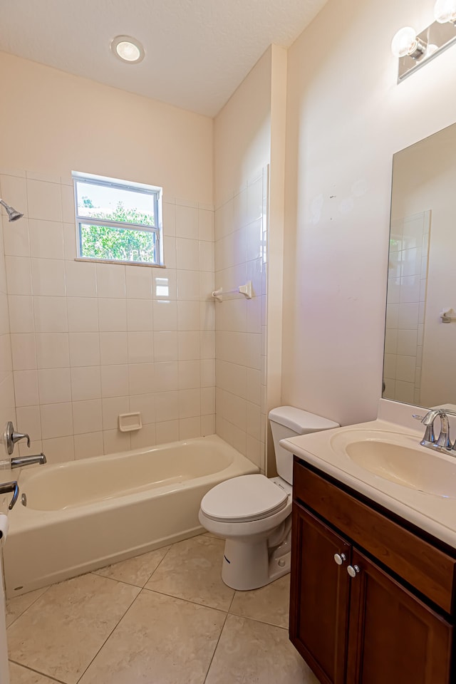 full bathroom featuring tile patterned flooring, tiled shower / bath, vanity, and toilet