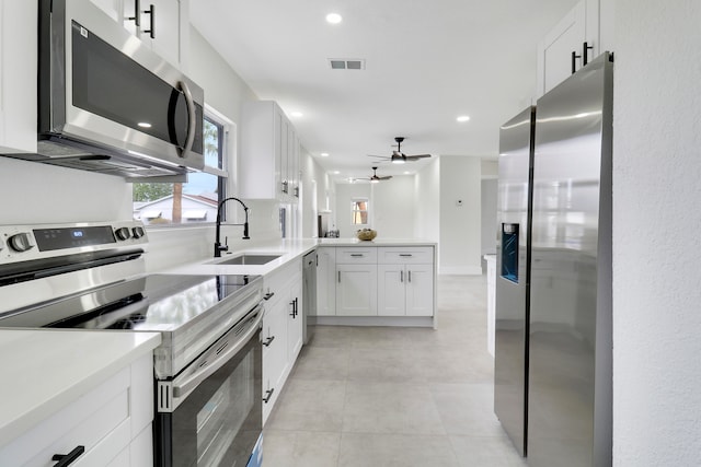 kitchen with kitchen peninsula, appliances with stainless steel finishes, ceiling fan, sink, and white cabinets