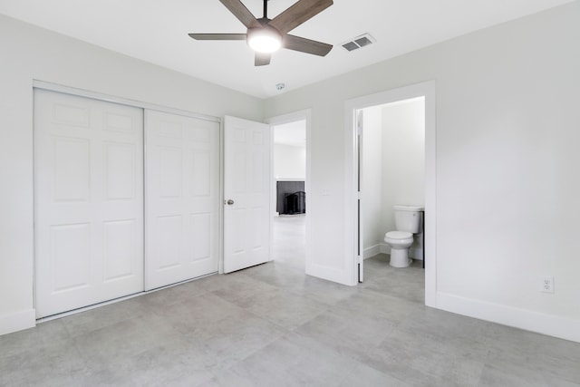 unfurnished bedroom with ceiling fan, a closet, and ensuite bath