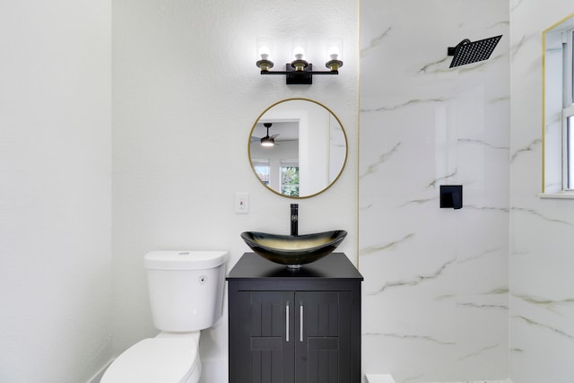 bathroom with vanity, ceiling fan, toilet, and tiled shower