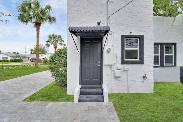 view of exterior entry featuring a yard