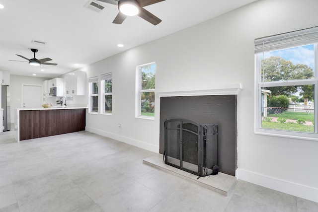 unfurnished living room with ceiling fan, a healthy amount of sunlight, and sink