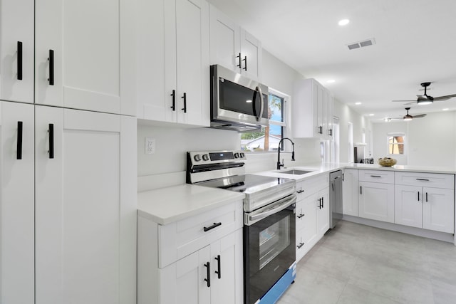 kitchen featuring kitchen peninsula, stainless steel appliances, ceiling fan, sink, and white cabinets