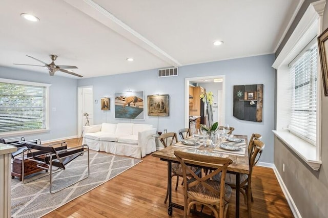 dining space with ceiling fan, hardwood / wood-style floors, and beamed ceiling