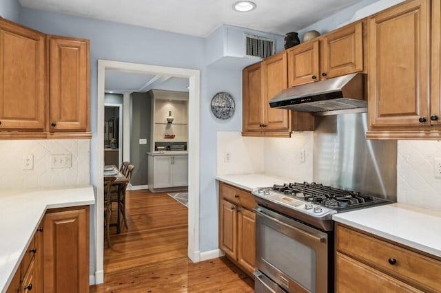 kitchen with light wood-type flooring, backsplash, and stainless steel range with gas stovetop