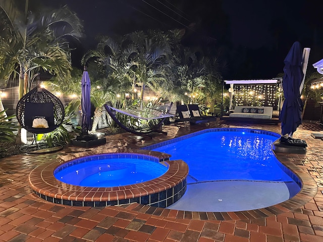 pool at twilight with an in ground hot tub and a patio