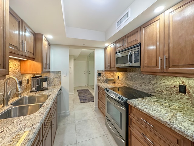 kitchen with light stone counters, sink, stainless steel appliances, and tasteful backsplash