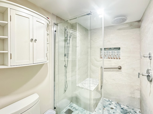 bathroom with a shower with door and toilet