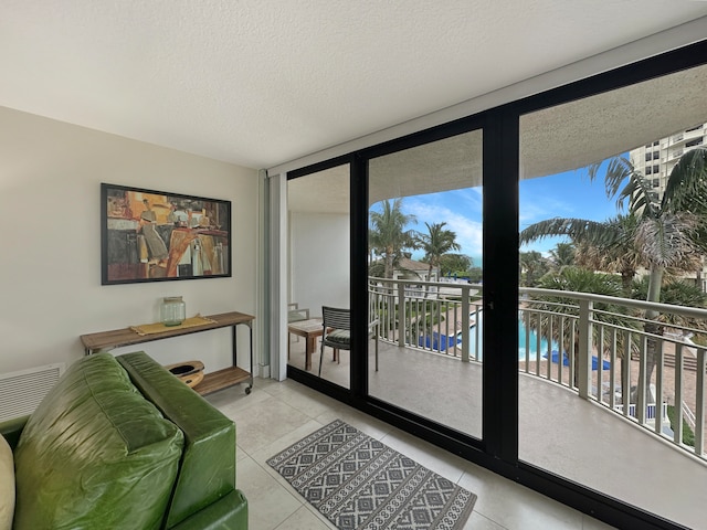 doorway featuring a water view, light tile patterned floors, and a textured ceiling