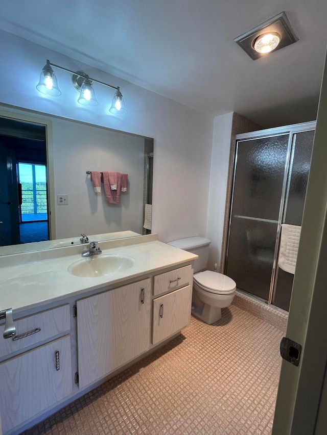 bathroom featuring vanity, toilet, and a shower with shower door