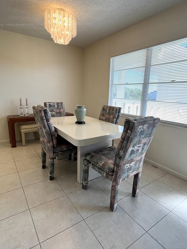 dining space with light tile patterned floors, a chandelier, and a textured ceiling