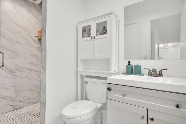 bathroom with vanity, toilet, and a tile shower