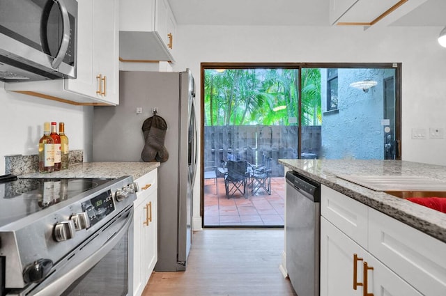 kitchen featuring light hardwood / wood-style floors, light stone countertops, white cabinetry, and appliances with stainless steel finishes