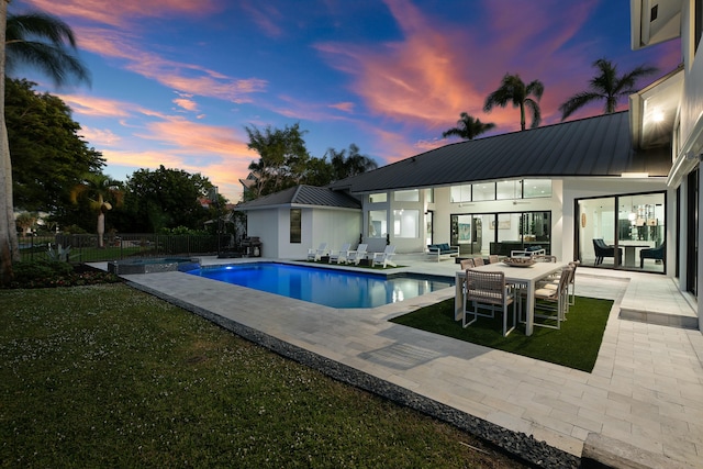 pool at dusk featuring an outdoor hangout area, a patio area, and a yard