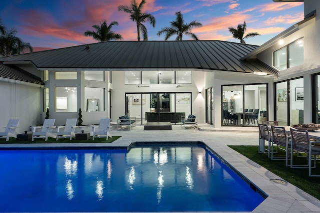 pool at dusk featuring an outdoor hangout area and a patio area