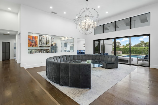 living room with bar, a towering ceiling, dark hardwood / wood-style floors, and a notable chandelier