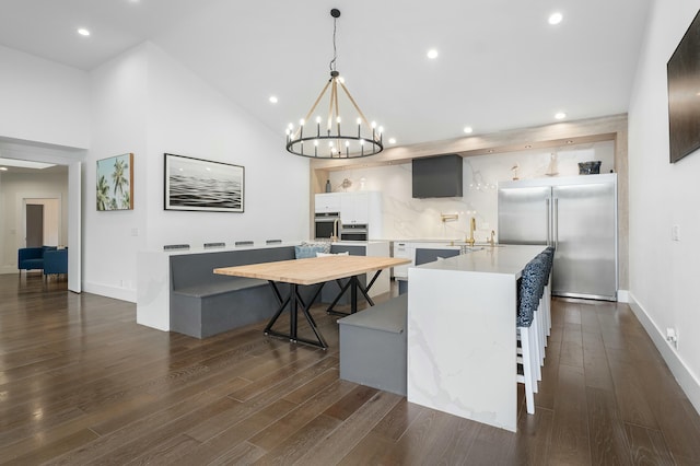 kitchen with stainless steel appliances, dark hardwood / wood-style flooring, high vaulted ceiling, decorative light fixtures, and a kitchen island