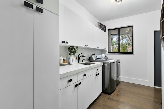 clothes washing area featuring washer and dryer, dark hardwood / wood-style flooring, cabinets, and sink