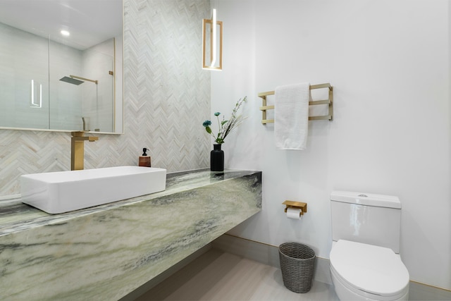 bathroom featuring sink, toilet, walk in shower, and tile walls