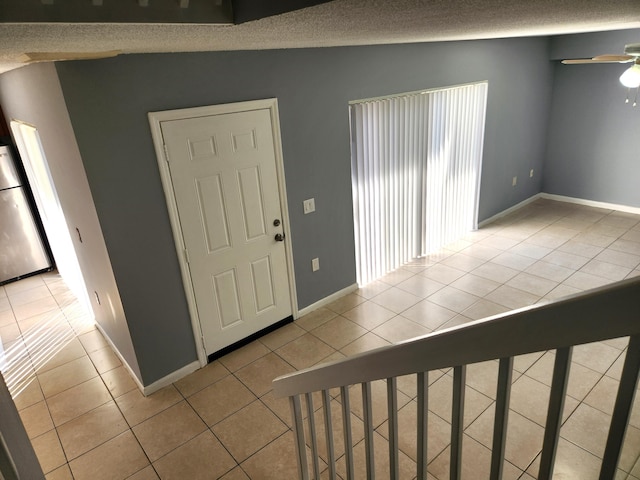 foyer with ceiling fan, light tile patterned floors, a textured ceiling, and vaulted ceiling