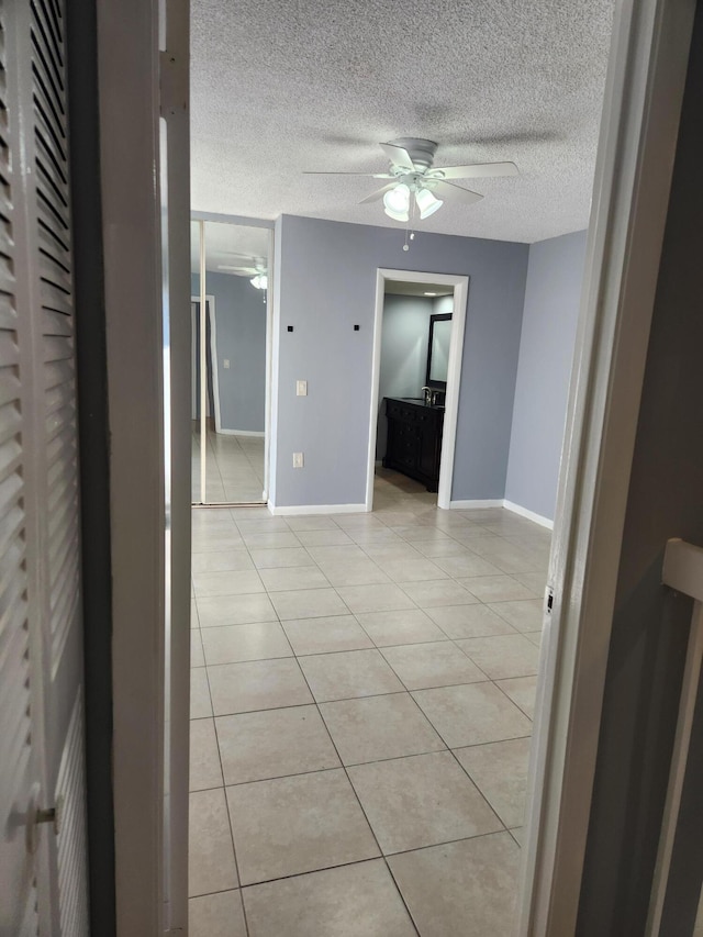 corridor with light tile patterned floors and a textured ceiling