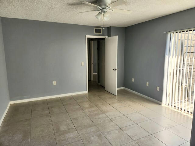 spare room with ceiling fan, light tile patterned floors, and a textured ceiling