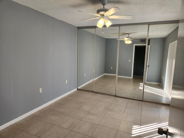 unfurnished bedroom featuring ceiling fan, light tile patterned flooring, a textured ceiling, and a closet