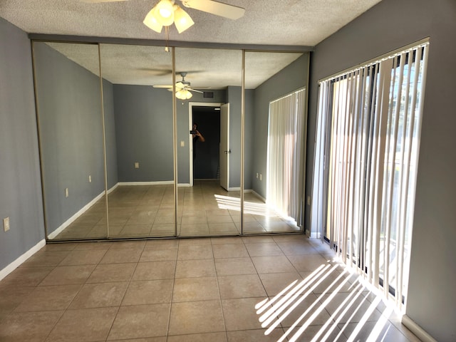 unfurnished bedroom with light tile patterned flooring, a textured ceiling, a closet, and ceiling fan