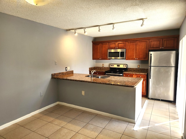 kitchen featuring sink, rail lighting, a textured ceiling, appliances with stainless steel finishes, and kitchen peninsula